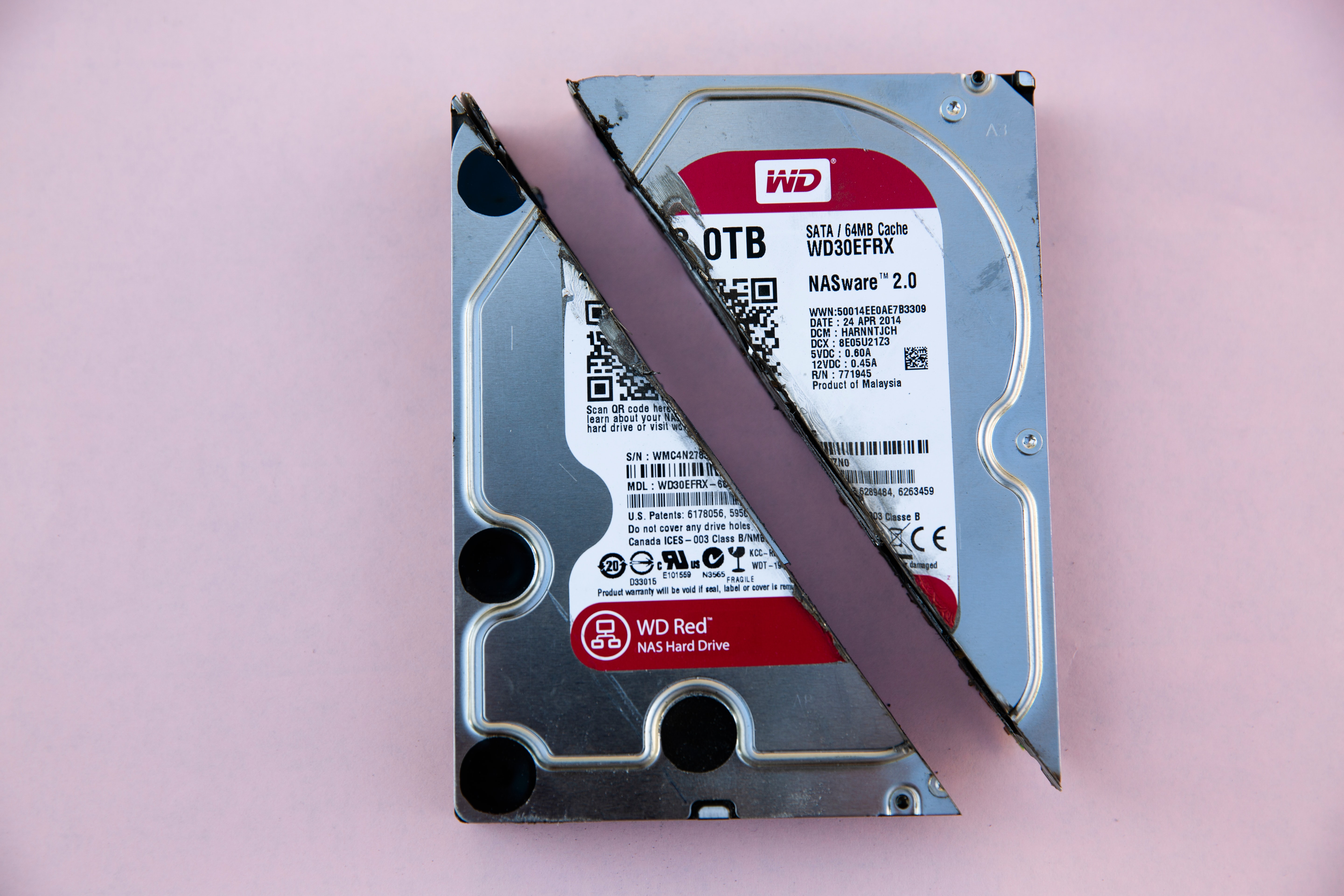 A WD Red harddrive cut in half on a pink background